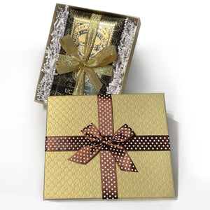 An image of a gold gift box with brown ribbon with white dots, opened with a package of chocolate bars inside surrounded by crinkle paper.