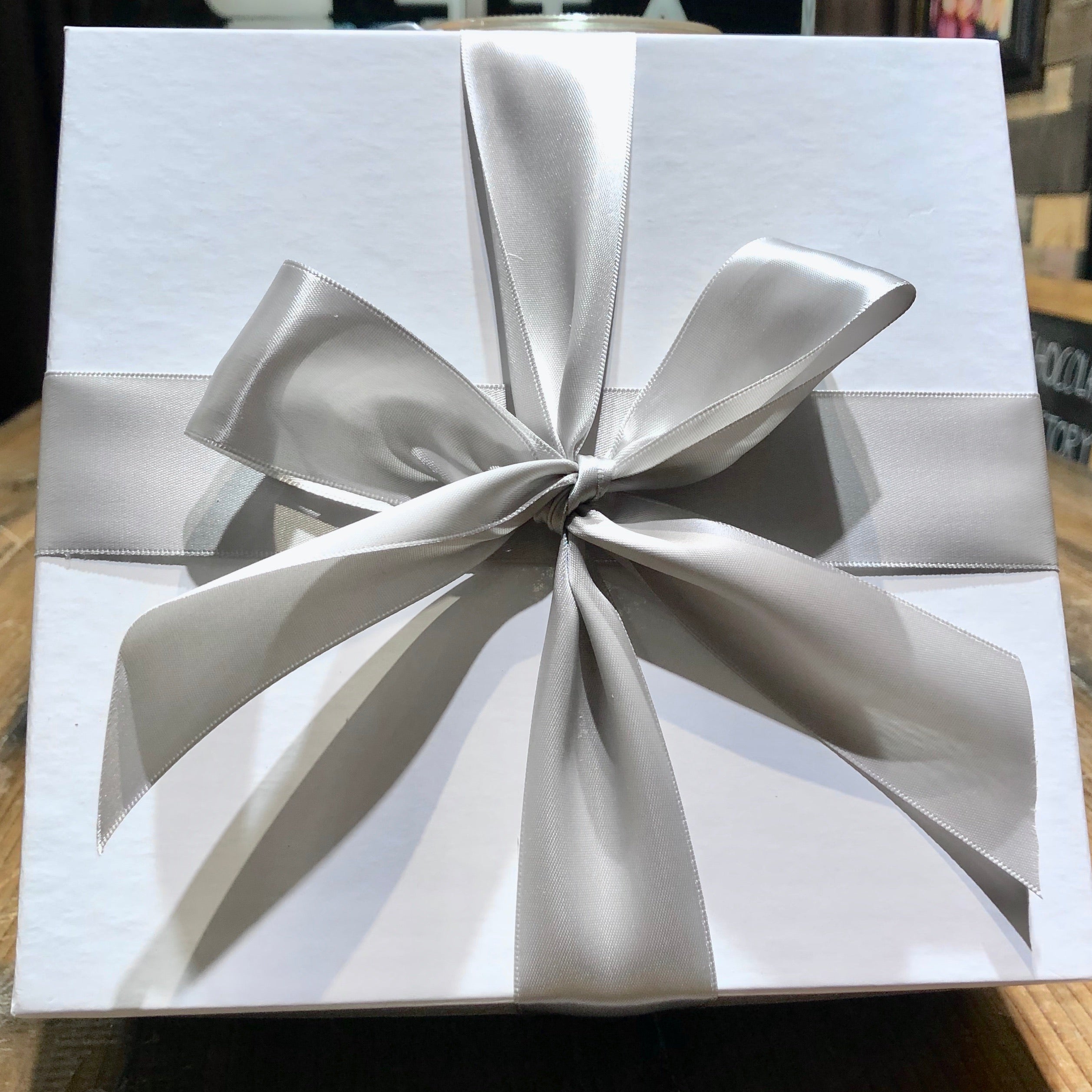 An image of a white gift box with silver ribbon