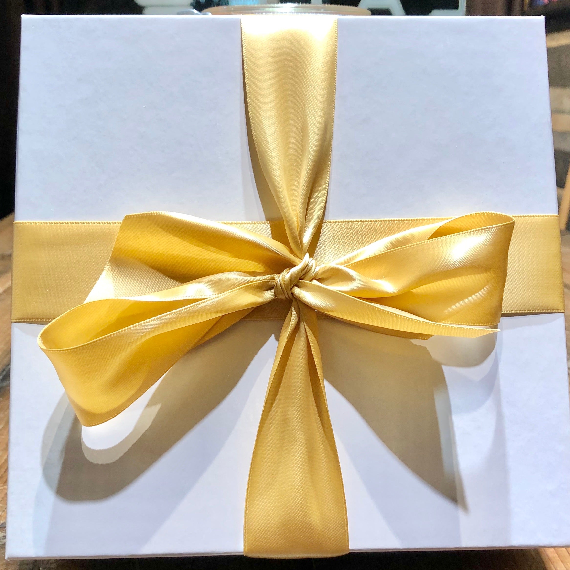 An image of a white gift box with gold ribbon
